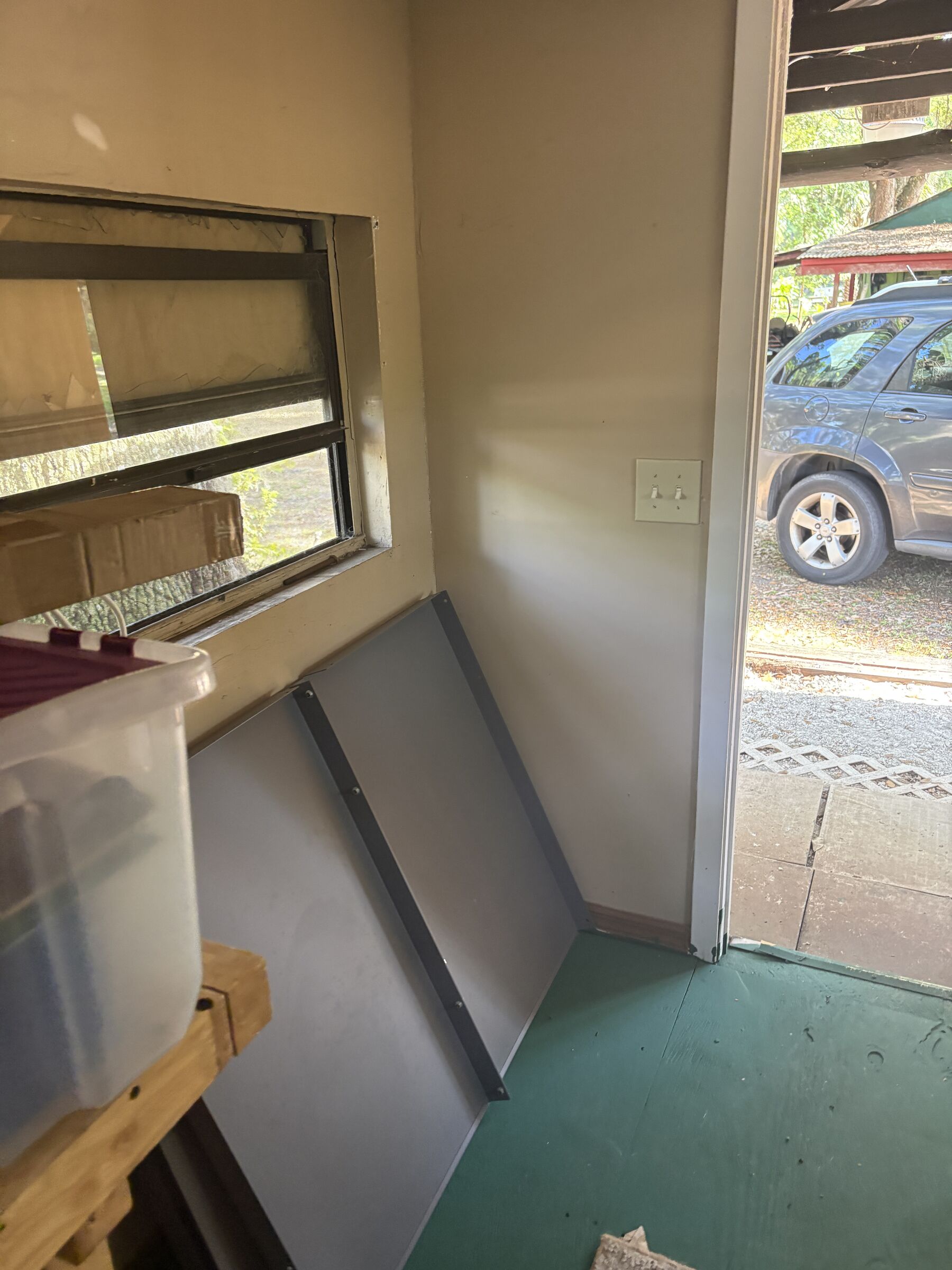 From inside by the door, looking out past the jamb to the porch and the car