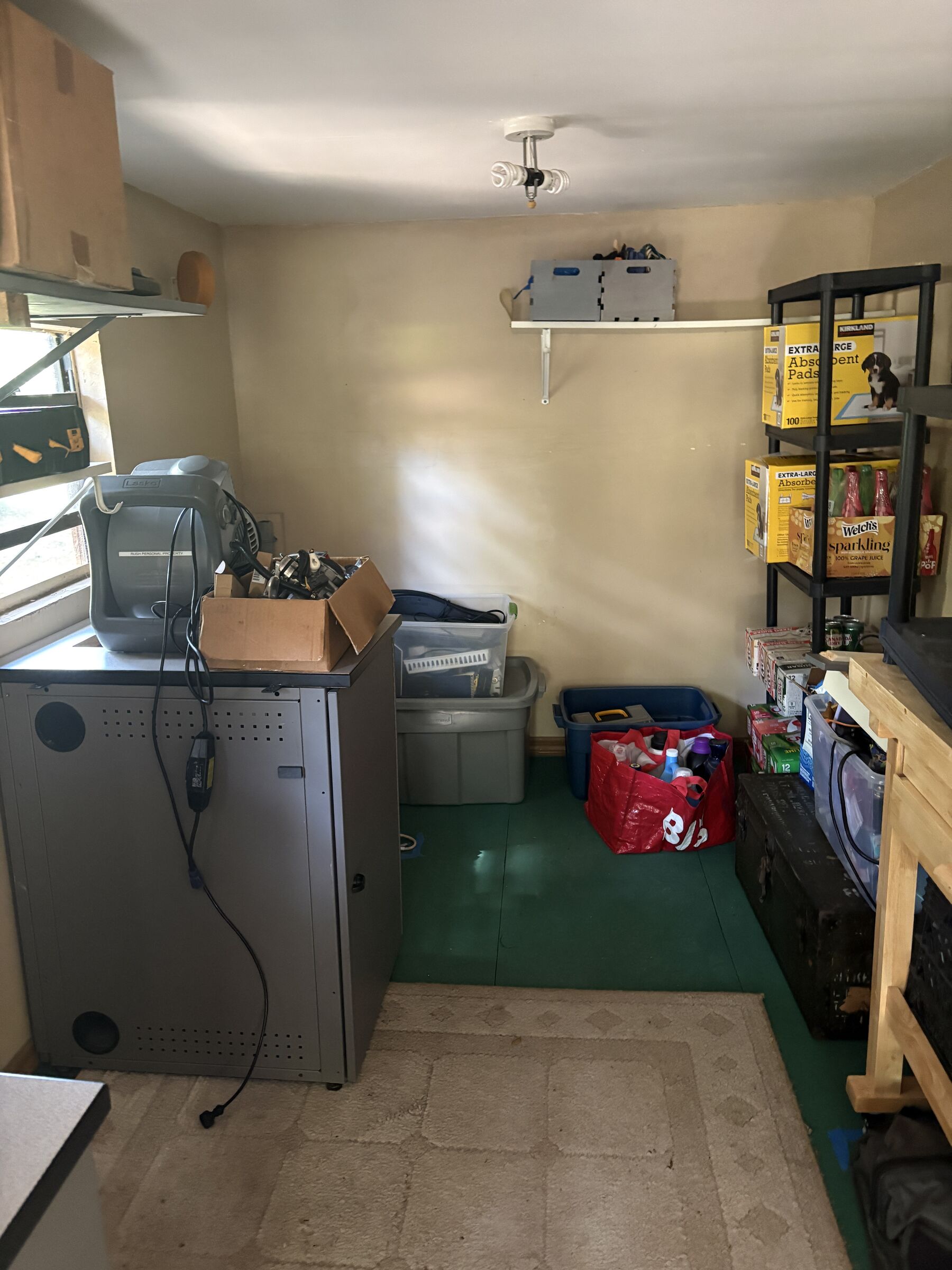 Moving in: green painted floor, shelving, boxes and a tool cabinet